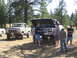 1979 Ford Bronco - Two off-road vehicles are parked in a wooded area, with several people gathered around the Jeep.