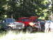 1979 Ford Bronco - Three pickup trucks, including a 1979 Ford F-150, are parked outdoors near trees.