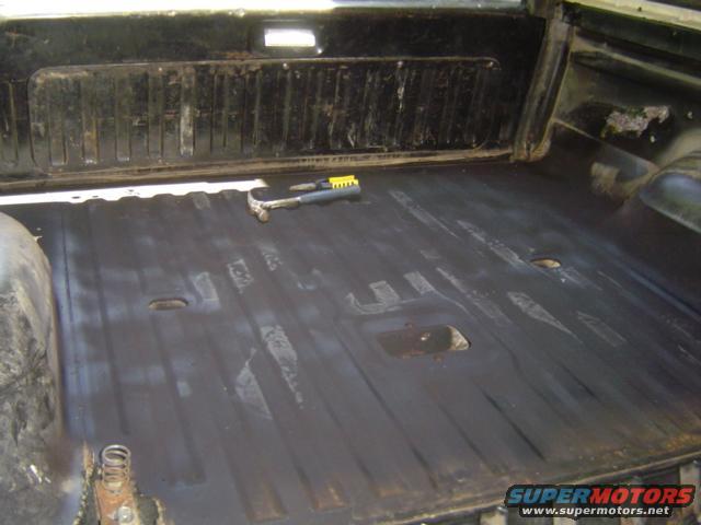 Interior cargo area with black floor and ribbed wall panel. A hammer rests on the floor