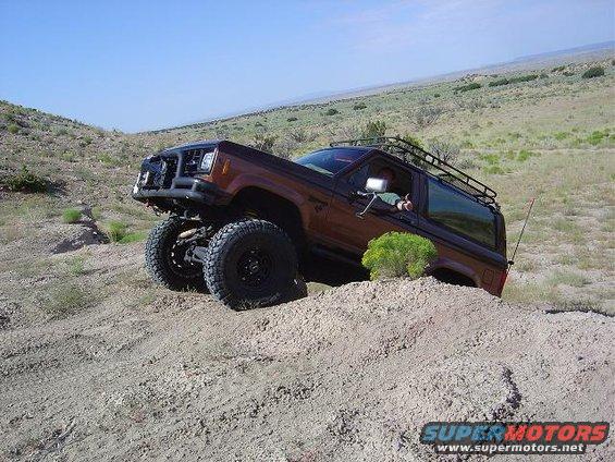 Brown SUV with roof rack on a dirt hill, lifted suspension, off-road tires