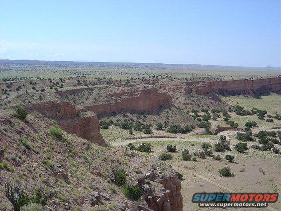 Desert landscape with mesas and sparse vegetation, Supermotors logo visible