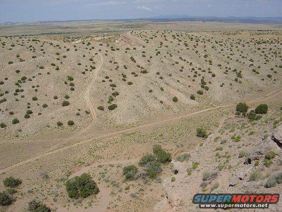 Desert landscape with scrub brush and dirt roads, Supermotors logo visible