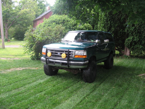 Green 1996 Ford Bronco parked on grass, front view, with smiley face fog lights