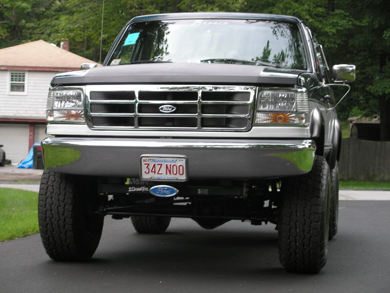 Dark green Ford Bronco front view, lifted with off-road tires, chrome grille, and Massachusetts license plate