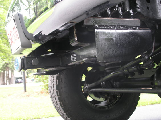 Close-up of a vehicle's rear bumper, showing a trailer hitch receiver and a license plate