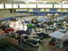 1975 Ford Bronco - Many cars are on display at an indoor automotive event, with spectators walking around.
