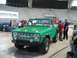 1975 Ford Bronco - A bright green 1975 Ford Bronco is showcased at an indoor event with spectators observing.