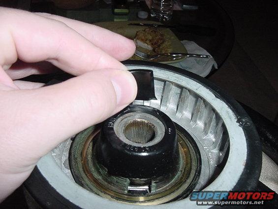 Hand reaching into a circular car part with visible internal components