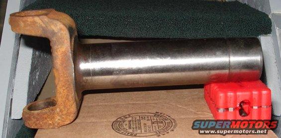 Rusted driveshaft slip yoke on a cardboard box with a red plastic support