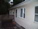 2004 Ford Crown Victoria - A house exterior shows a wooden deck, railing, door, and windows under a cloudy sky.
