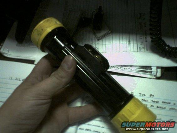 Black flashlight with yellow ends held in hand over papers