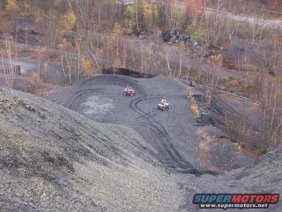 Two ATVs on a coal pile with tire tracks