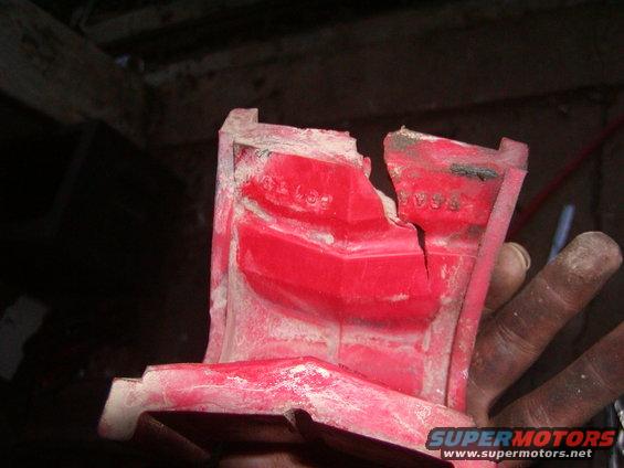 Cracked red plastic part with white dust and visible stamped numbers