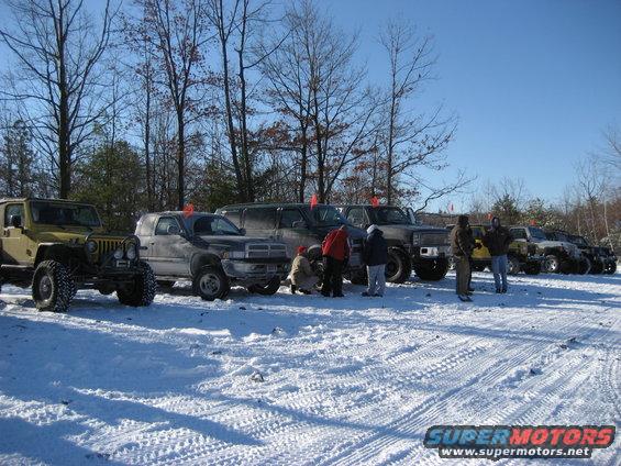 Several off-road vehicles parked in the snow on a sunny day