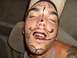 1992 Ford Bronco - A man with marker drawings on his face appears to be asleep or passed out inside a vehicle.