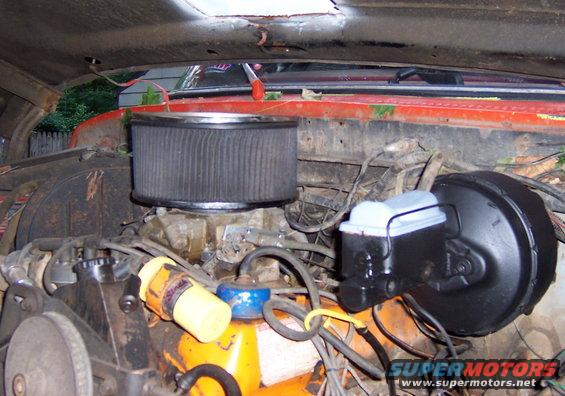 Engine bay showing air filter, carburetor, and brake booster. Some wiring and hoses are visible
