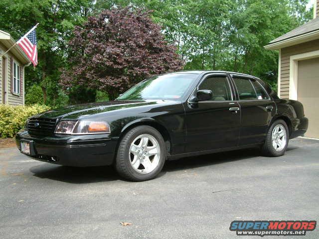 Black 2002 Ford Crown Victoria parked in a driveway next to a house