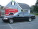 2002 Ford Crown Victoria - A black 2002 Ford Crown Victoria sedan is parked in front of a house with a fire truck to its left.