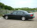 2002 Ford Crown Victoria - Side view of a black 2002 Ford Crown Victoria LX Sport parked near a wooden fence and sand dunes.
