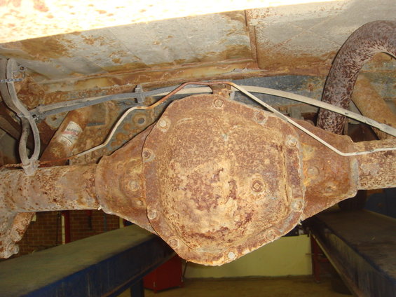 Rusty rear differential and exhaust pipe of a vehicle, viewed from underneath