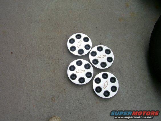 Four Chevrolet hubcaps with black lug nut holes and a central Chevrolet logo