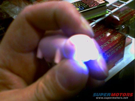 Hand holding a glowing object with "SHOCKING AUTOPSY" books in background