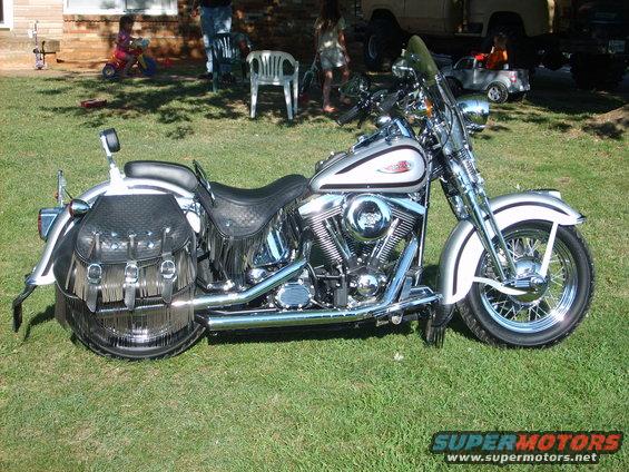 Silver 1999 Harley-Davidson Softail motorcycle with black leather saddlebags and fringe, parked on grass