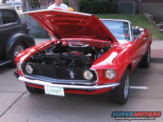 Red 1969 Ford Mustang convertible with hood open, showing engine. Front view