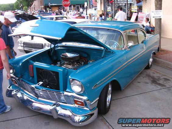 Blue 1956 Chevrolet Bel Air coupe with hood open, chrome grille, and custom wheels
