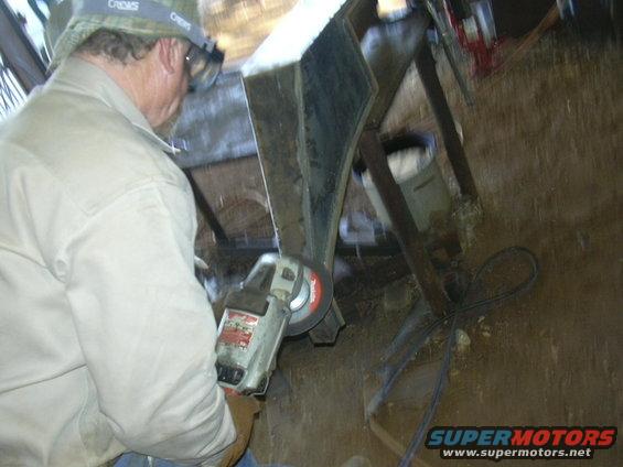 Man in tan shirt and hat grinding metal with an angle grinder