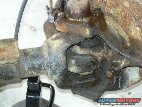 Close-up of a rusty front axle differential housing with a driveshaft U-joint visible