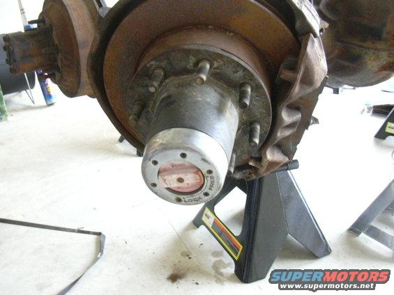 Close-up of a vehicle's front wheel hub with a locking mechanism, resting on jack stands