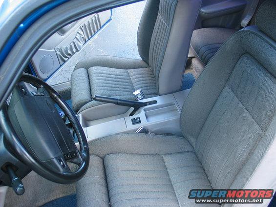Blue 1990 Ford Mustang interior showing grey fabric seats, dashboard, steering wheel, and center console