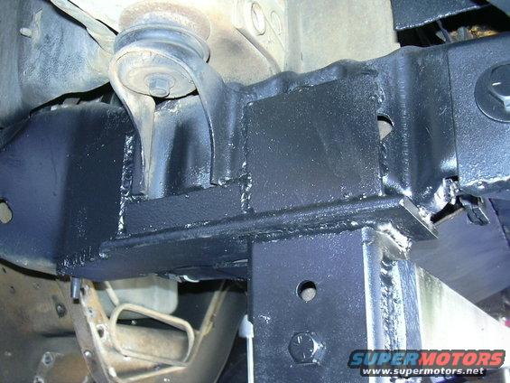 Close-up of welded metal brackets on a vehicle frame, likely for a suspension modification