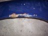 Blue car fender with chipped paint and rust spots