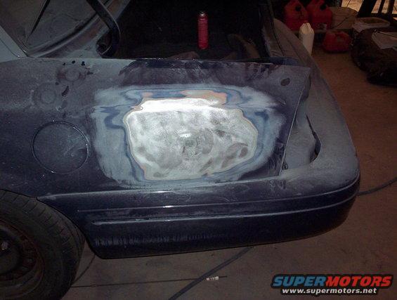 Dark blue car rear quarter panel with body filler and primer