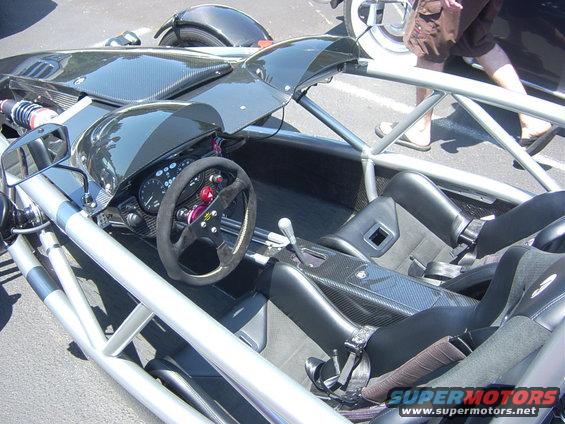 Interior of a lightweight sports car with a roll cage, racing seats, and a steering wheel