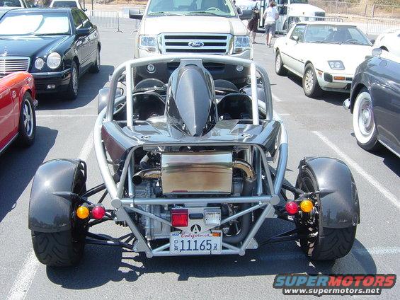 Rear-engine sports car with exposed engine and roll cage, California license plate 11165