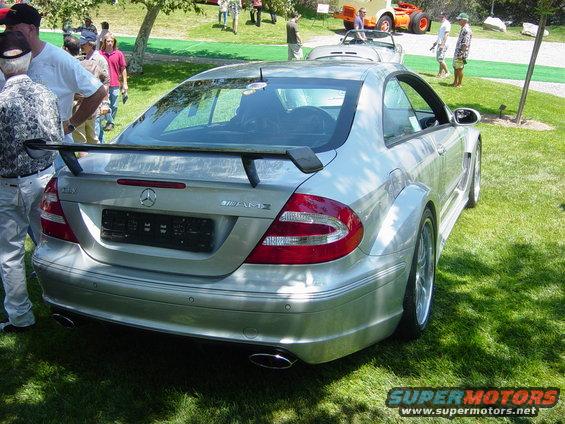 Silver Mercedes-Benz coupe with a large rear spoiler and wide body kit parked on grass