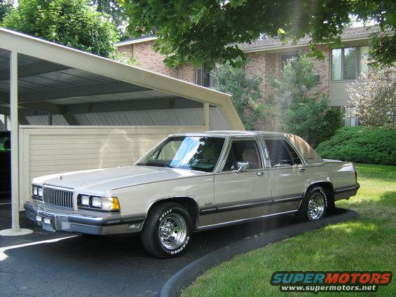 Tan 1988 Mercury Grand Marquis sedan parked on asphalt with a carport overhead