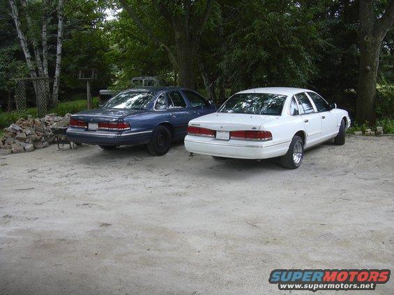 1997 Ford Crown Victoria and a blue Ford Crown Victoria parked on gravel
