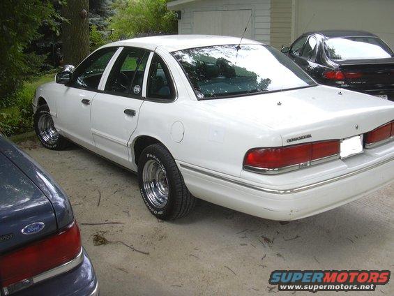White 1997 Ford Crown Victoria with chrome wheels parked next to another car