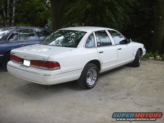 1997 Ford Crown Victoria, rear 3/4 view, parked on concrete next to a blue sedan