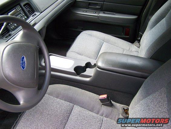 Ford steering wheel, center console with cup holders, and front seats. This is the interior of a 2003 Ford Crown Victoria