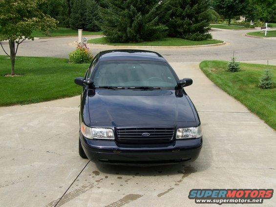 Dark blue sedan parked on a driveway, front view. Looks like a 2003 Ford Crown Victoria