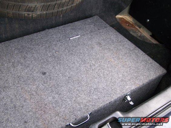 Spare tire and carpeted subwoofer box in a car trunk