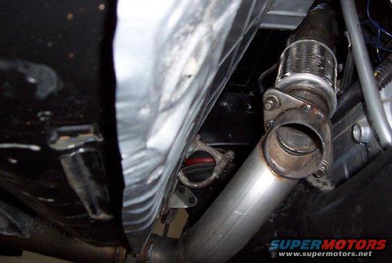 Underside view of a car's exhaust pipe connection with a flexible joint