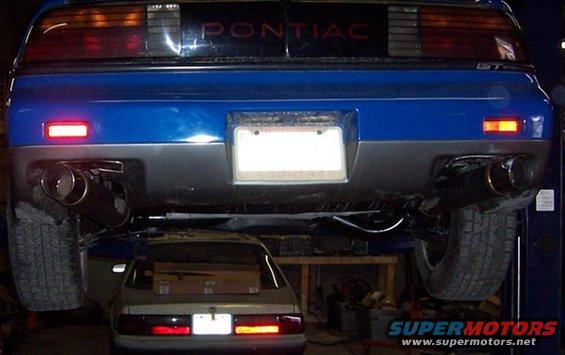 Rear of blue 1988 Pontiac Fiero GT on lift, another car below