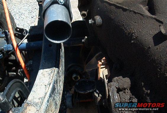 Close-up of an exhaust pipe and some suspension parts, possibly from a truck or SUV
