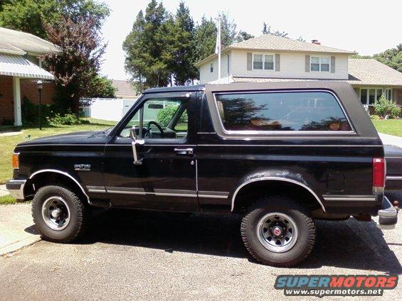 Black Ford Bronco parked in a driveway. Side view